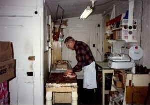 Dick Winking hand cutting meat in the back kitchen area in January 1993.