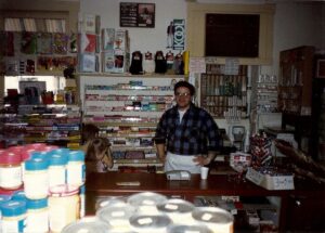 Frank Winking working behind the counter in January 1993.  Notice the kids picking out their penny candy to Franks right.