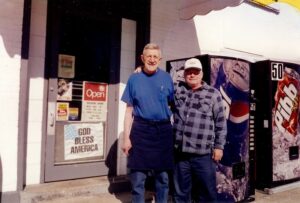 Dick Winking and customer Jim Gregory standing out in front of the store.