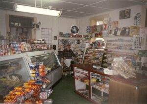 Dick Winking sitting on his stool in the back corner of the store.